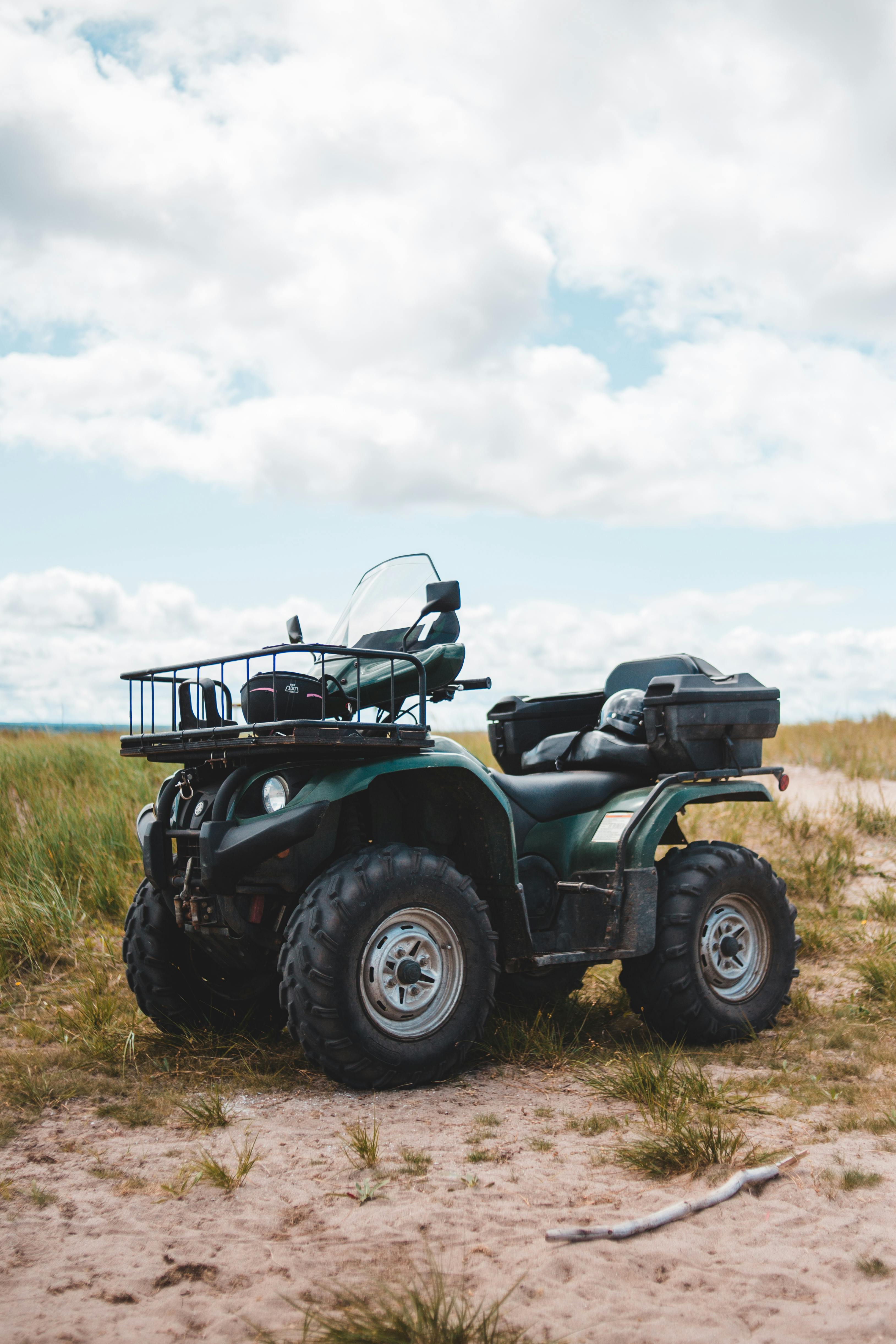 A robust ATV stands parked in a vast grassland under a cloudy sky, showcasing outdoor adventure.
