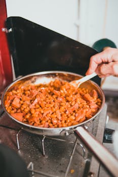 A close-up of baked beans being cooked in a pan on a stove.
