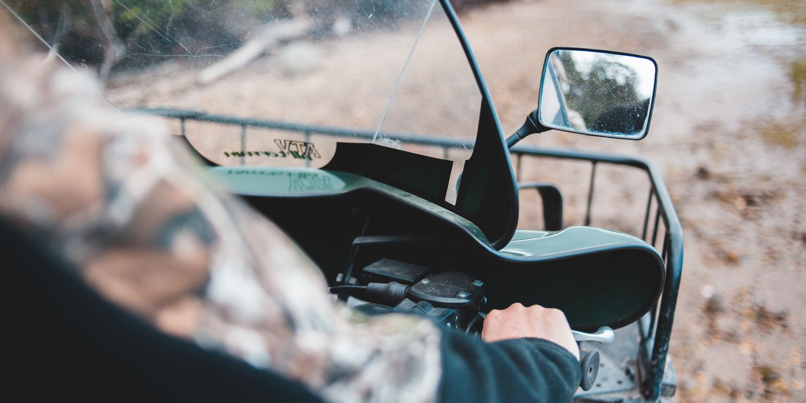 A rider driving a quad bike along a muddy off-road trail