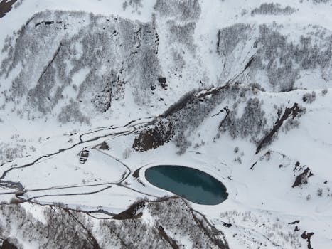 Scenic aerial view of a frozen lake surrounded by snow-covered mountains in winter.