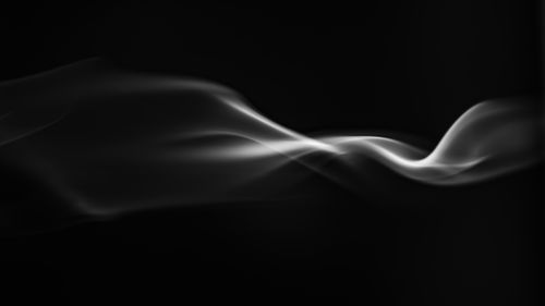 Free Graceful smoke trails forming abstract shapes against a black background. Stock Photo
