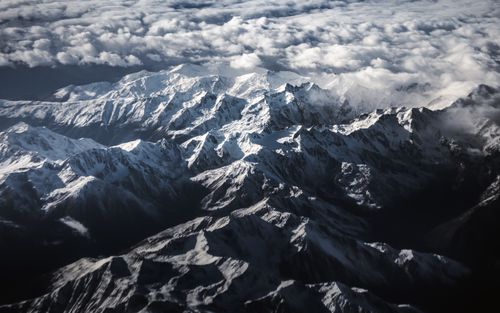 Free A breathtaking aerial view of a snow-capped mountain range under a cloudy sky in Italy. Stock Photo