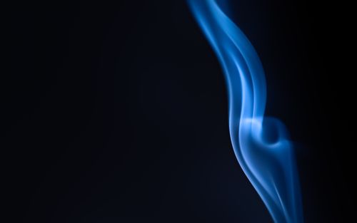Free Elegant blue smoke swirling against a black background, perfect for artistic and abstract themes. Stock Photo