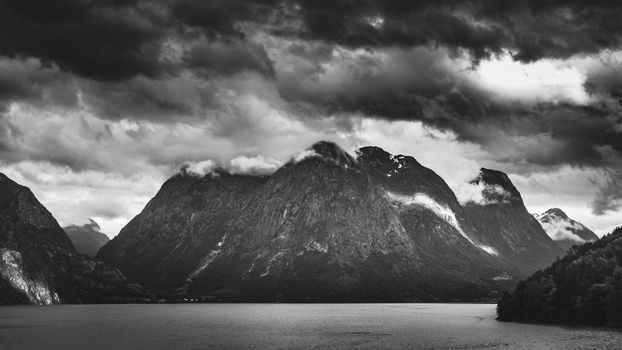 Breathtaking view of Norwegian mountains under a moody, cloudy sky in black and white.