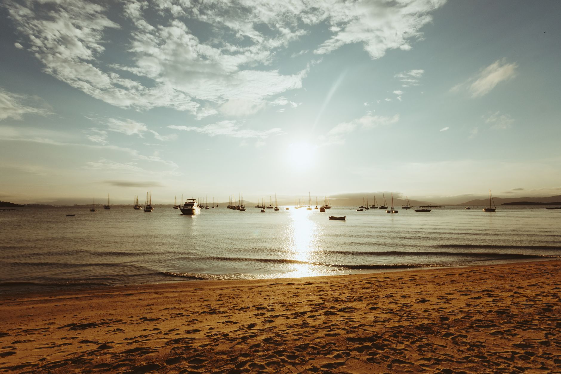 Serene sunset at Florianópolis beach with boats dotting the tranquil seaside waters.