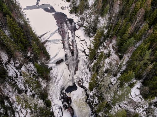 Free A breathtaking aerial view of a frozen waterfall surrounded by snowy forests in Lier, Norway. Stock Photo