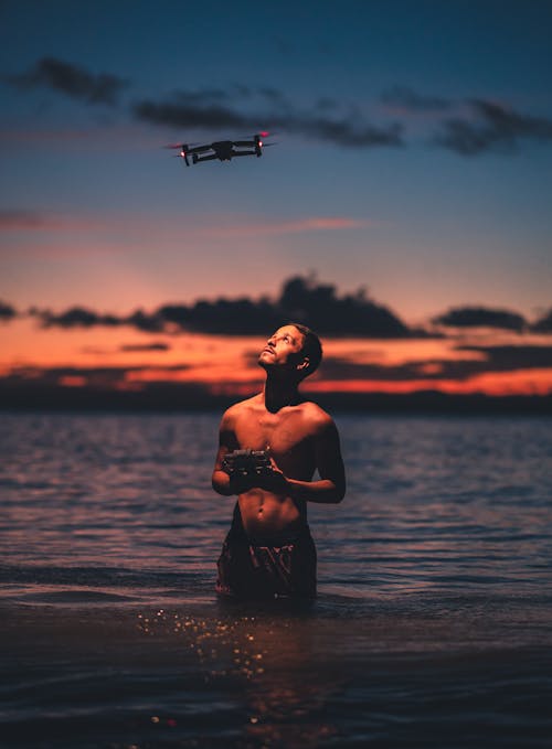 Free Drone Flying above a Shirtless Man in Water Stock Photo
