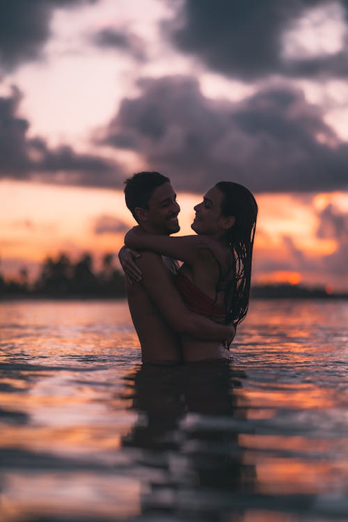 Couple Hugging Each Other in  Water During Sunset