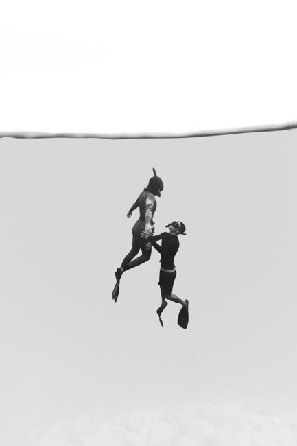 Artistic black and white image of two divers gracefully swimming underwater.