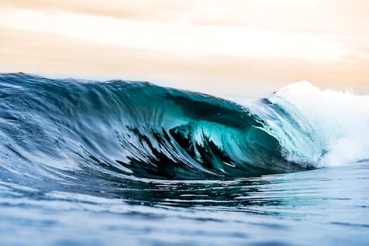 A stunning close-up of a crashing ocean wave with vibrant colors under the early morning sky.