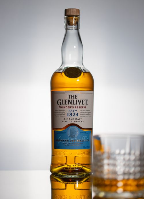Free Elegant single malt Scotch whisky bottle with glass against studio background. Stock Photo
