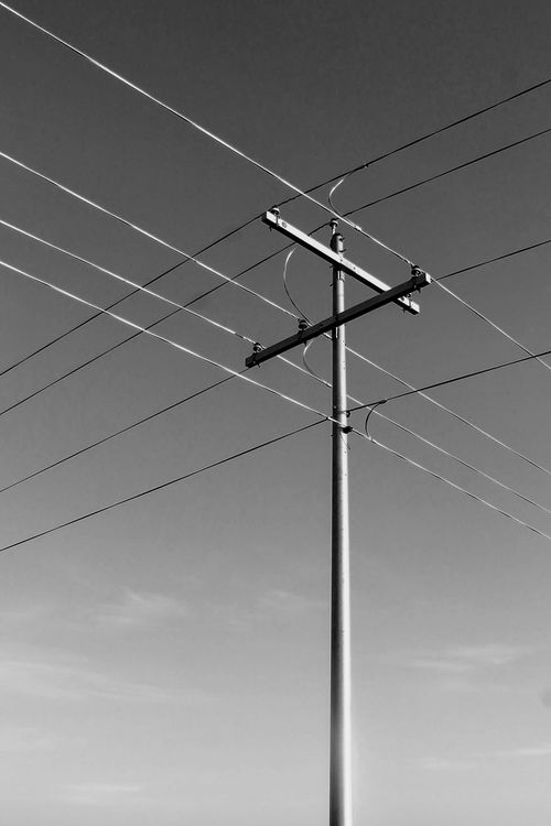 Free Black and white image of a utility pole with power lines against a clear sky. Stock Photo