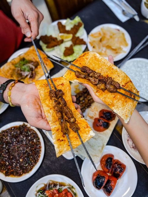 Free Overhead view of delicious grilled meat skewers served on flatbread with various side dishes. Stock Photo