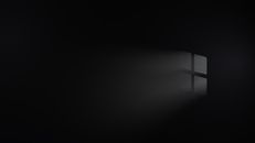 Atmospheric image of light streaming through a window, creating a stark contrast against a dark background.
