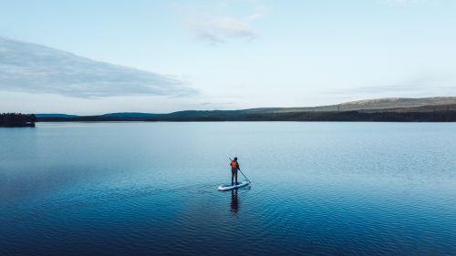 Free A lone paddle boarder navigates a calm lake in Murmansk, Russia. Stock Photo