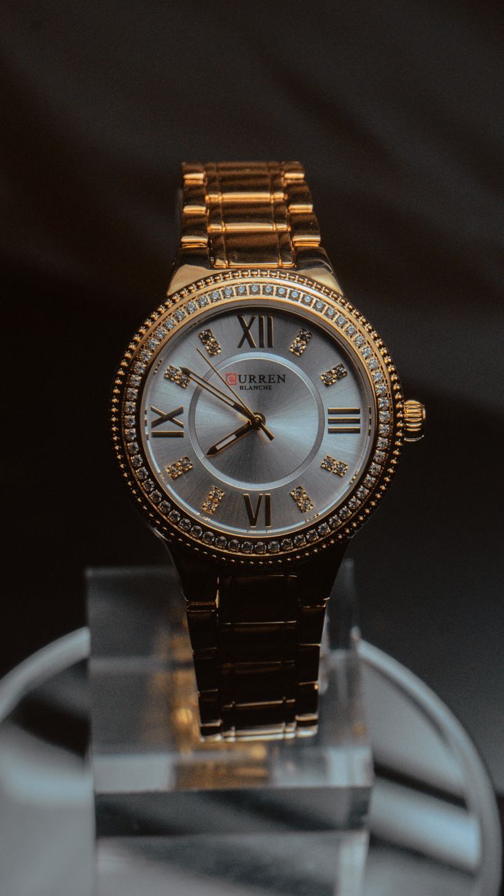 Luxury gold and silver wristwatch with Roman numerals elegantly displayed on a stand.