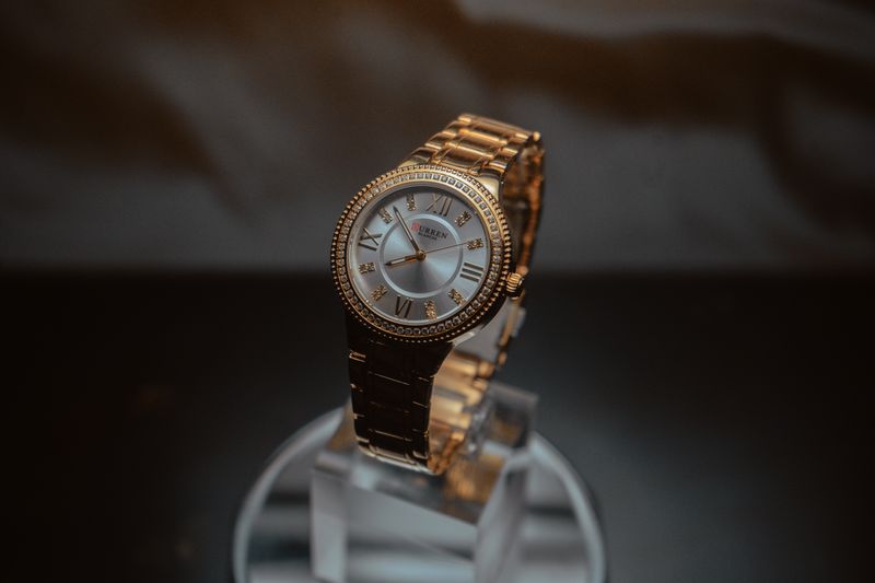 Stylish gold wristwatch showcased on a reflective stand with a dark background