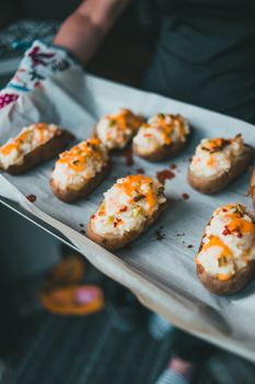 Close-up of mouth-watering twice-baked potatoes with cheese and bacon on a tray.