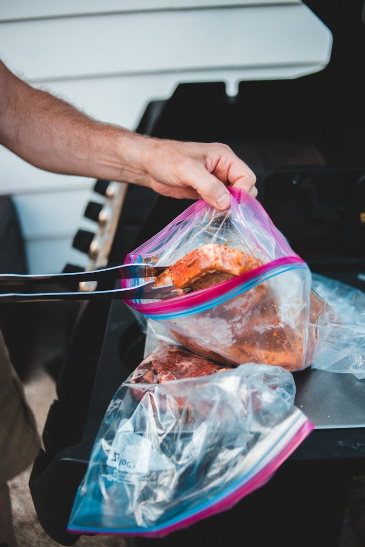 Person Holding Clear Plastic Pack With Meat