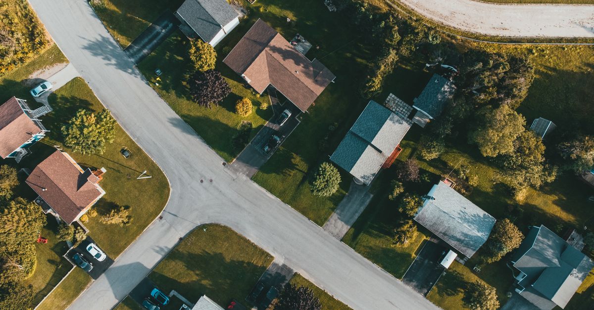 Bird's eye view of a suburban neighborhood with tree-lined streets and houses.