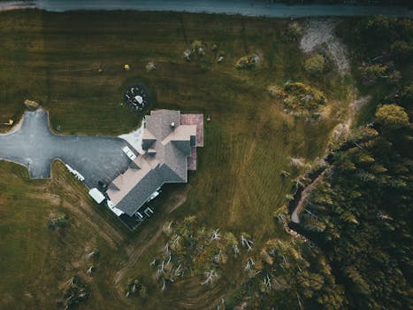 A stunning aerial shot of a suburban house surrounded by lush greenery and a driveway.