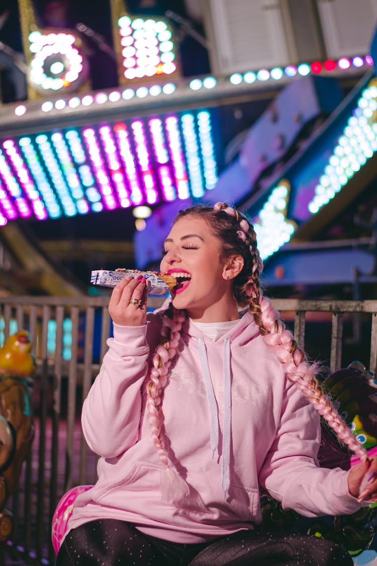 Woman In Pink Hoodie Eating Hotdog