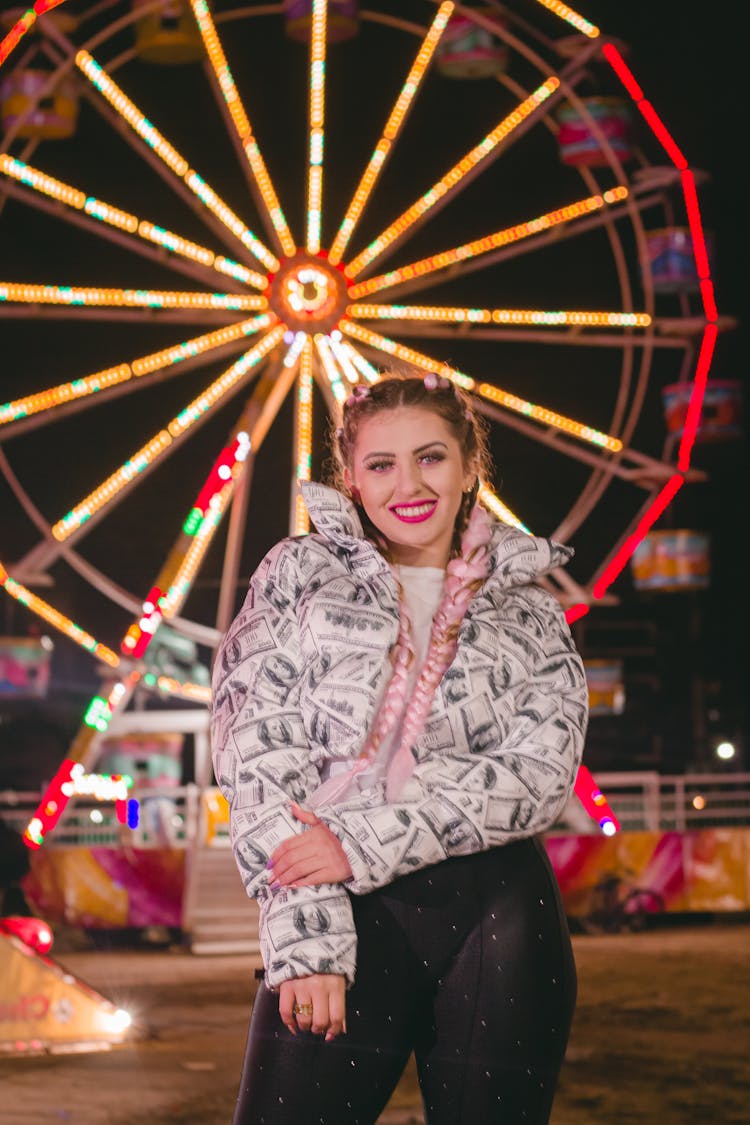 A Woman In Printed Jacket Standing Near The Ferris Wheel At Night