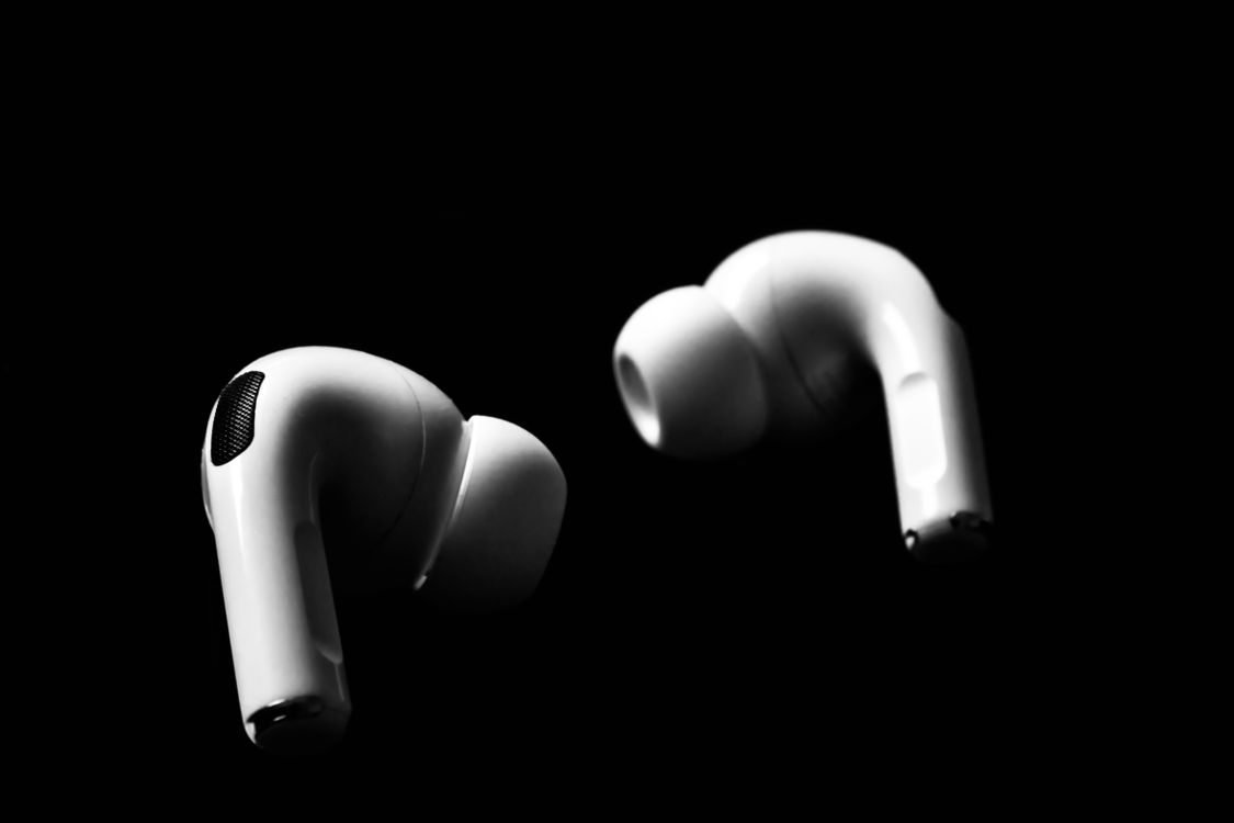 White wireless earbuds isolated against a dramatic dark background