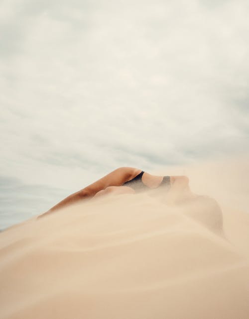 Free A Woman in a Bikini Lying on Sand Stock Photo