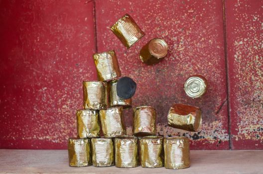 A stack of tin cans in motion against a textured red wall, creating a rustic and vintage feel.