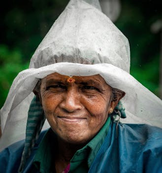 A senior South Asian woman smiling in rain gear, showcasing cultural attire with a serene expression.