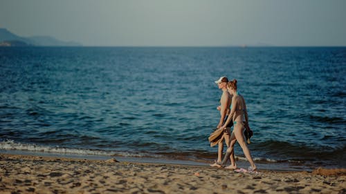 무료 낮에 해변에서 산책하는 커플 스톡 사진