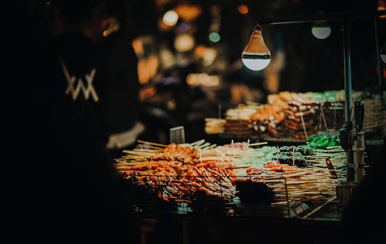 Vibrant street food skewers at a lively night market under warm lighting.