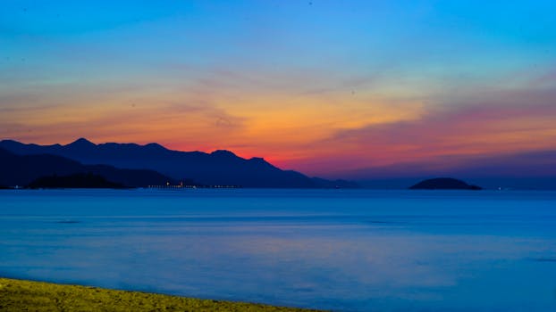 鲜艳的色彩呈现在令人惊叹的热带日落、平静的海洋以及遥远的岛屿和山脉轮廓上