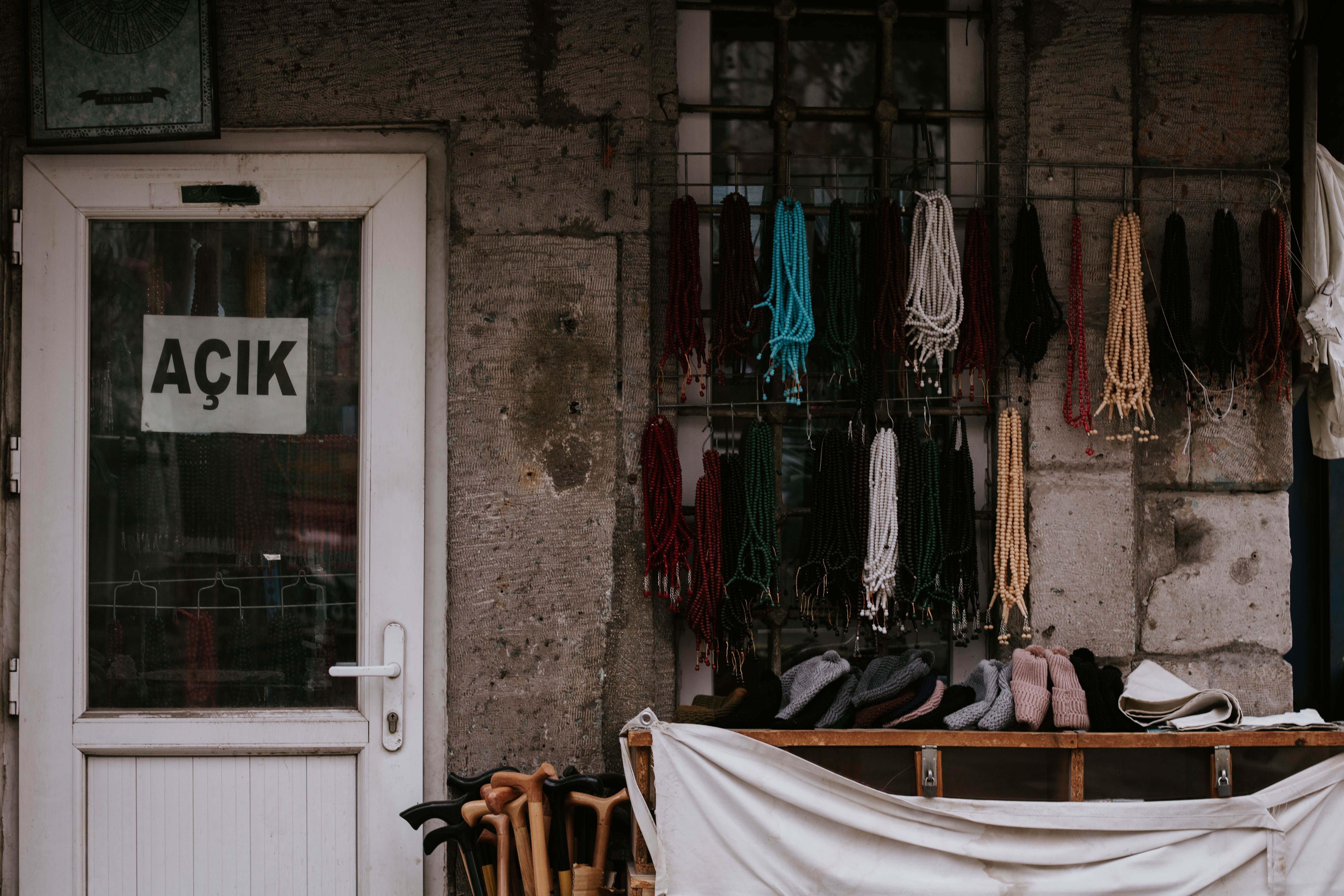Outdoor display of colorful beads and accessories in front of an open door with Turkish sign.