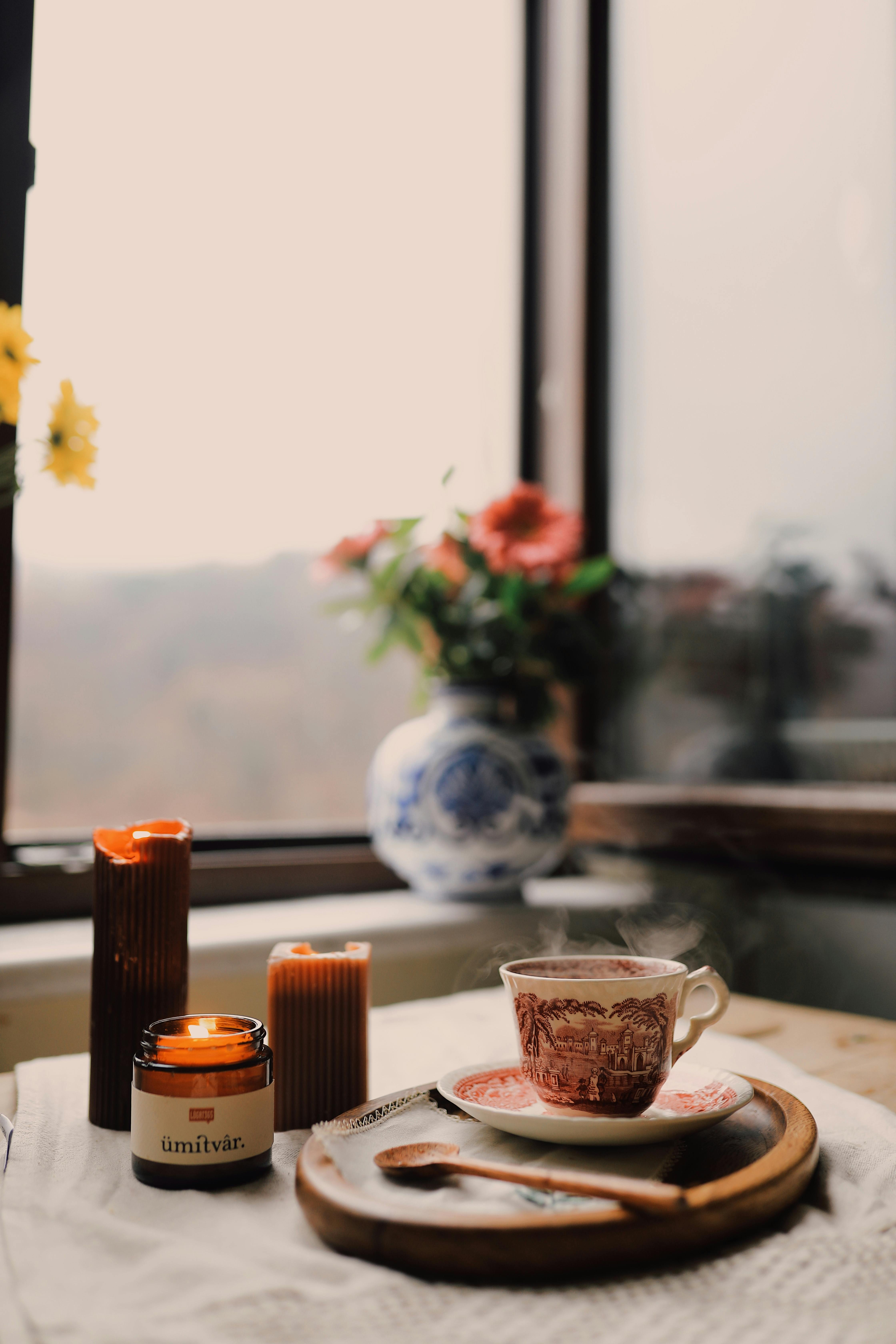 Warm morning setup with coffee, candles, and flowers by the window. Perfect for serene moments.