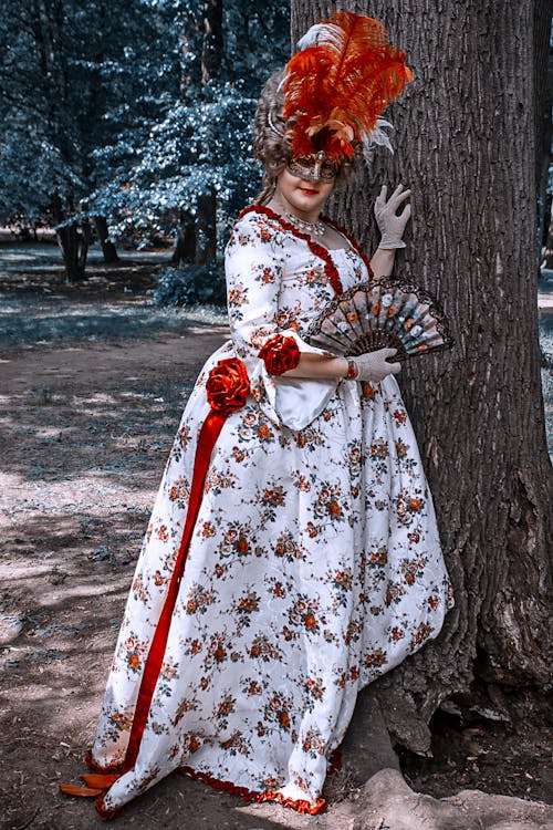 Woman in White and Red Dress Costume standing beside a Tree