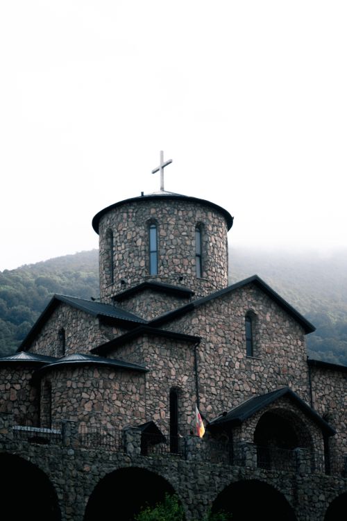 Free A stone monastery nestled in a misty mountain valley, symbolizing tranquility and religious architecture. Stock Photo