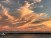 日落令人惊叹，平静的水面上旋转的云层图案营造出宁静的景观