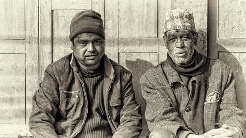 Free Two men in traditional attire sit outside in Nepal, capturing local culture. Stock Photo