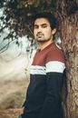 Man Wearing Long Sleeve Shirt Standing Beside a Tree