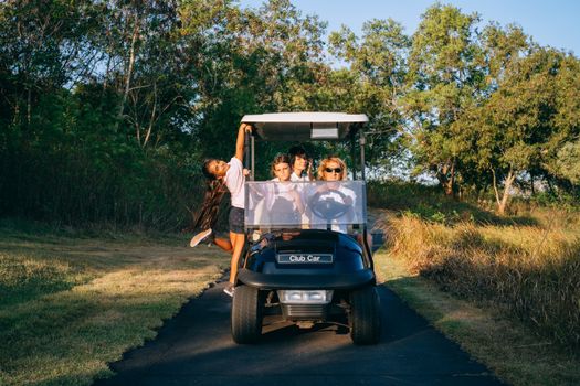 Family having fun on a golf buggy ride on a sunny day surrounded by nature.