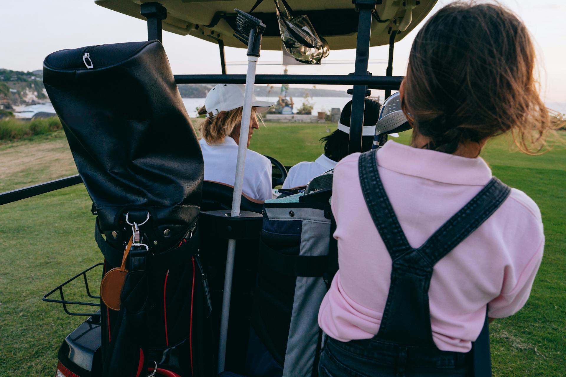 Group enjoying a golf cart ride on a picturesque course at sunset.