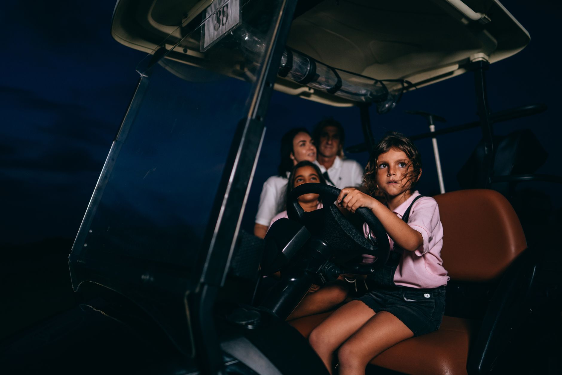 A family with kids enjoying a nighttime drive in a golf cart, showcasing fun and adventure.