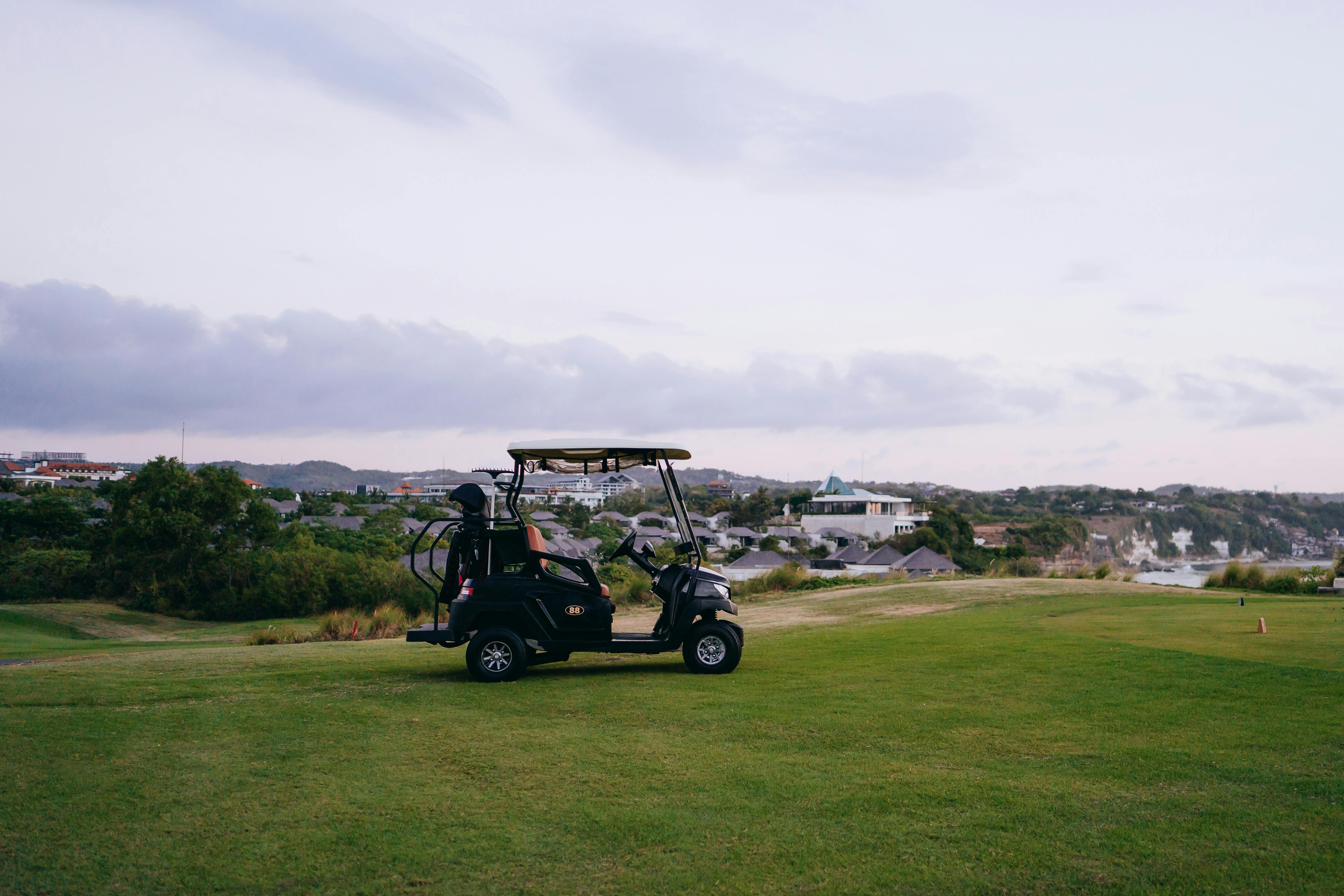 A tranquil golf course scene with a golf cart set against a scenic landscape during twilight.