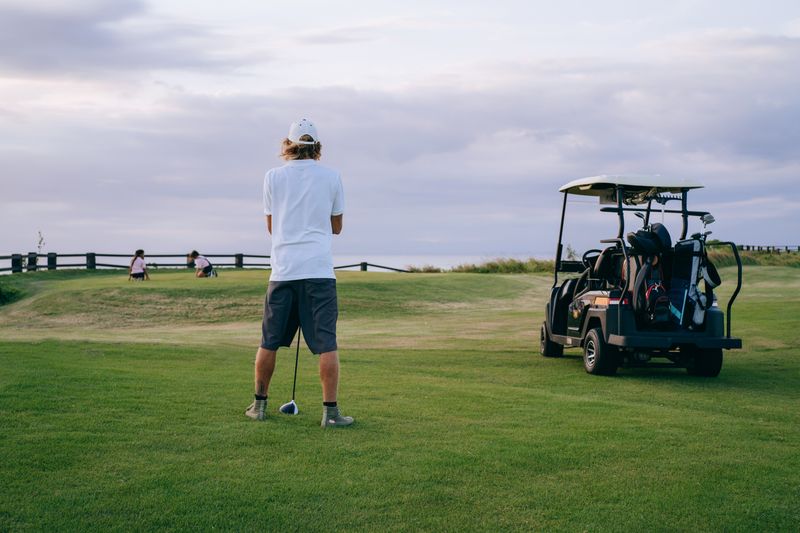 Golfer in a white polo shirt taking a swing on the course