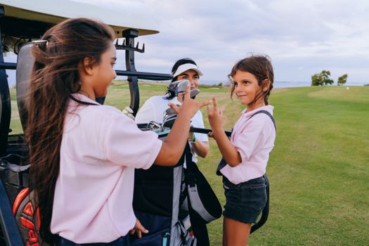 Three children having a playful moment with golf equipment on a sunny day outdoors.