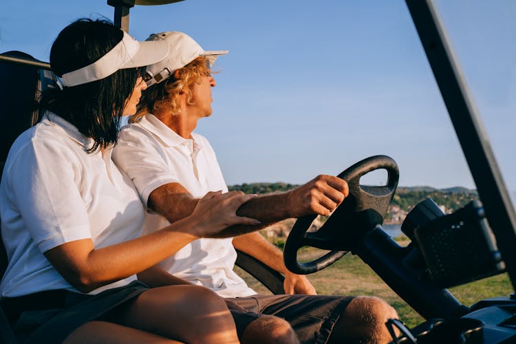 Man And Woman Sitting On Golf Buggy