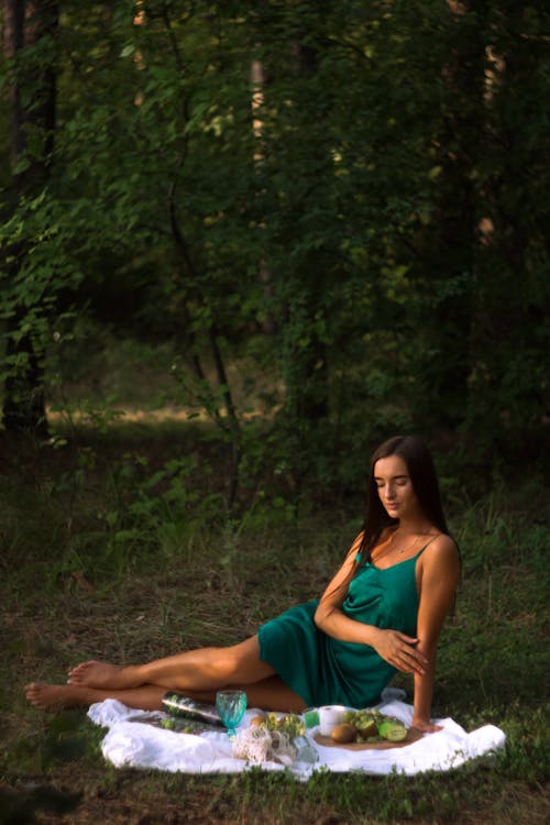Free Woman Wearing Green Dress Sitting on a Picnic Blanket Stock Photo