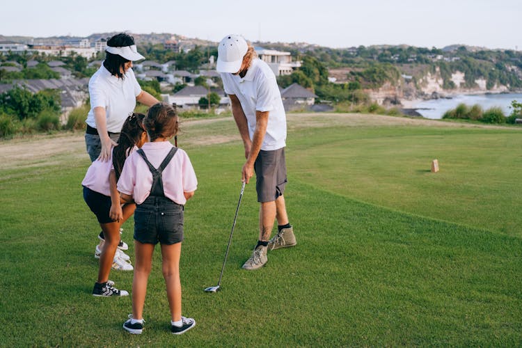 Family Playing Golf On Green Grass Field